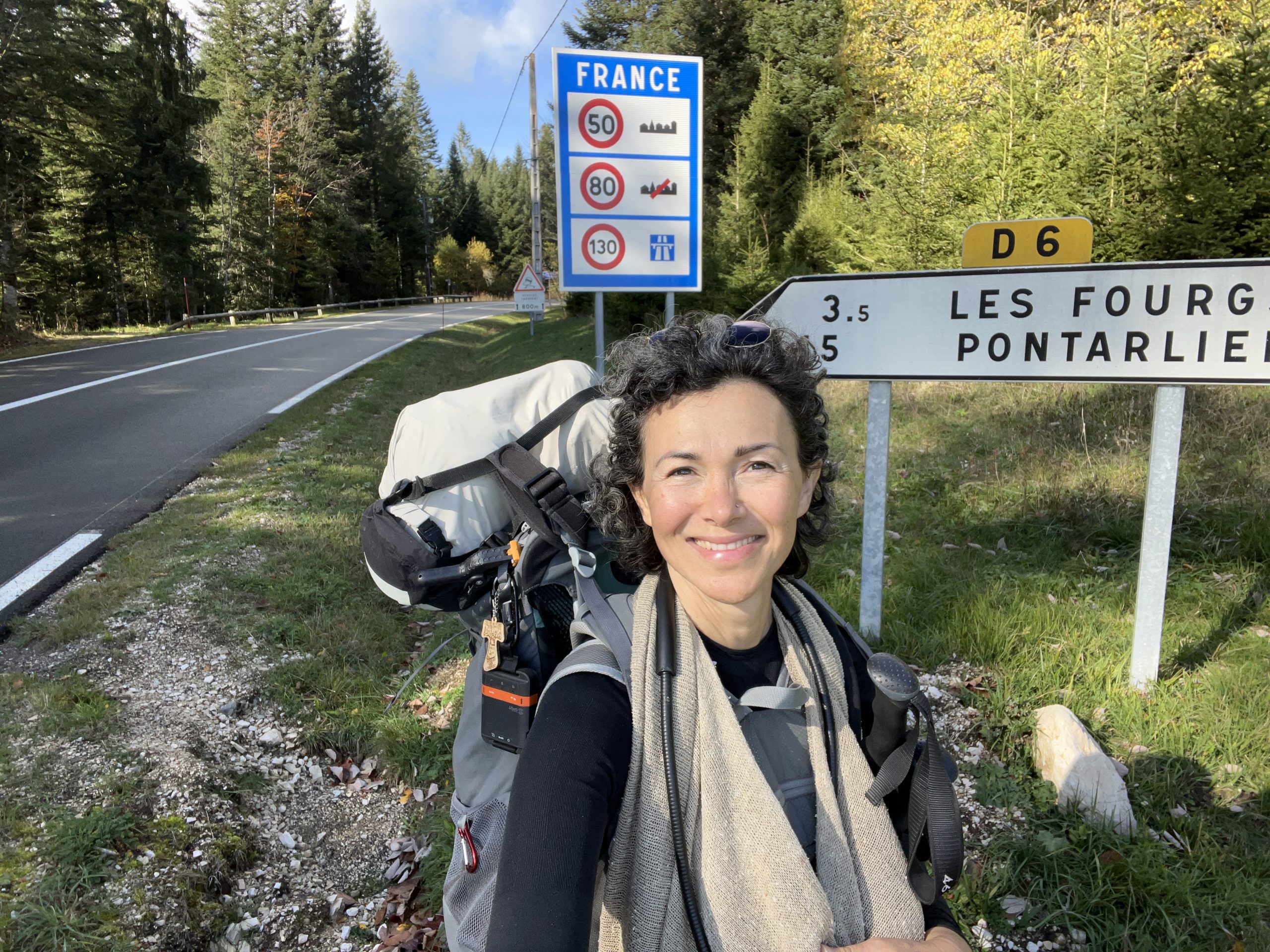 Donna sorridente con zaino lungo la strada in Francia